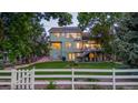 Spacious backyard with manicured lawn, white picket fence, mature trees, and back of home at 6266 Holman St, Arvada, CO 80004