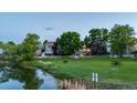 Scenic view of homes bordering a pond with lush green space and a white picket fence at 6266 Holman St, Arvada, CO 80004