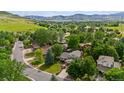 Scenic aerial view of a home surrounded by mature trees, lush landscaping, and picturesque mountain views at 5971 Windy St, Golden, CO 80403