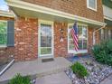 Close-up of a brick home's entrance with a secure screen door, accent window and an American flag at 7391 S Knolls Way, Centennial, CO 80122