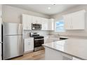 Well-lit kitchen featuring white cabinets, stainless steel appliances, and a spacious countertop area at 48275 Shetland Dr, Bennett, CO 80102