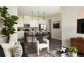 Comfortable living room showcasing a stylish kitchen island with seating, modern sofa and chair, and contemporary decor at 6153 N Ceylon St # 305, Denver, CO 80249
