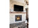 Close up of stone fireplace with a wood beam mantle and a flat screen television above at 1275 Washington Ave, Golden, CO 80401