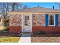 Charming brick home featuring a storm door entrance, blue shutters, and a well-maintained front lawn at 1257 Locust St, Denver, CO 80220