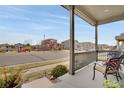 Inviting covered porch with comfortable seating, offering views of the neighborhood park and playground at 13475 Spruce St, Thornton, CO 80602