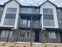 Modern townhome with a black-and-white facade, large windows, and a covered porch at 694 Saddle Dr, Erie, CO 80516