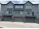 Contemporary townhome featuring garage doors and modern gray-tone exterior at 694 Saddle Dr, Erie, CO 80516