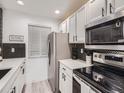 Stylish kitchen featuring white cabinetry, stainless steel appliances, and trendy black and white backsplash at 4068 S Atchison Way # 101, Aurora, CO 80014