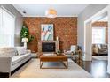 Cozy living room with exposed brick wall, fireplace, and neutral-toned furniture at 321 S Emerson St, Denver, CO 80209