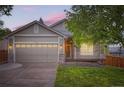 Traditional home showcasing an attached two-car garage, manicured lawn, and inviting front porch at 16179 W 70Th Pl, Arvada, CO 80007
