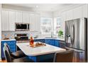 Modern kitchen featuring two-tone cabinets, stainless steel appliances, and a spacious island with seating at 1063 Roslyn Ct, Denver, CO 80230