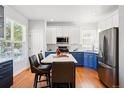 Bright kitchen showcasing white and blue cabinetry, stainless steel appliances, and a center island with bar stools at 1063 Roslyn Ct, Denver, CO 80230