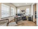 Bright home office featuring three windows, a modern desk with multiple monitors, and comfortable seating at 13329 Newport Cir, Thornton, CO 80602
