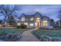 Inviting two-story home at dusk, showcasing a lit brick pathway and lush front yard at 8 Mountain Willow Dr, Littleton, CO 80127