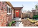 Charming brick home featuring a vibrant coral front door and a covered front porch at 3316 N Glencoe St, Denver, CO 80207