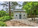 Small outbuilding featuring gray siding, a simple gable roof, and a glass door; surrounded by lush greenery at 7312 Marshall Rd, Larkspur, CO 80118
