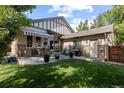 A tranquil backyard with a covered patio, dining set, lush lawn, and privacy landscaping for outdoor enjoyment at 652 Ulster Way, Denver, CO 80230