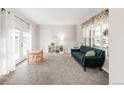 Cozy living room with bright windows, neutral carpet, and a comfortable blue sofa at 17294 W 60Th Ct, Arvada, CO 80403