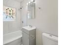 Bright bathroom featuring a tub with tile surround, decorative window and updated vanity at 2865 S Fairfax St, Denver, CO 80222