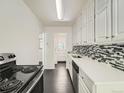Modern kitchen featuring white cabinets, stainless steel appliances, mosaic backsplash and hardwood floors at 2865 S Fairfax St, Denver, CO 80222