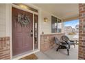 Inviting front porch with seating, brick accents, a decorative wreath and nice natural light at 17124 Mariposa St, Broomfield, CO 80023