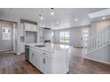 Open concept kitchen with white cabinetry, center island with sink, and view to living area at 24801 E 33Rd Dr, Aurora, CO 80019