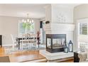 Open dining area featuring a fireplace, hardwood flooring, stylish chandelier, and abundant natural light at 1449 Braewood Ave, Highlands Ranch, CO 80129