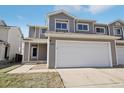 Two story house with a two car garage featuring gray siding and a front porch at 879 Canary Ln, Brighton, CO 80601