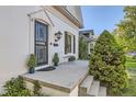 Inviting front porch with black wrought iron door, small table set, and manicured landscaping at 1006 S Emerson St, Denver, CO 80209