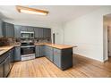 Well-lit kitchen featuring grey cabinets, butcher block countertops, and hardwood floors at 309 Lincoln Ave, Platteville, CO 80651