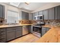 Modern kitchen featuring grey cabinets, a stainless steel range, and a mosaic backsplash at 309 Lincoln Ave, Platteville, CO 80651