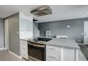 A cozy kitchen with stainless steel appliances, range hood and a grey and white backsplash at 1204 S Uvalda St, Aurora, CO 80012