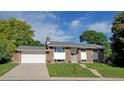 Charming brick home with well-manicured lawn, attached garage, and steps leading to the front door at 1733 S Urban Way, Lakewood, CO 80228