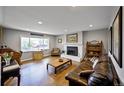 Cozy living room featuring hardwood floors, a brick fireplace, and natural light from a large window at 1733 S Urban Way, Lakewood, CO 80228