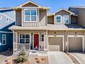 Charming townhome showcasing a bright red front door, paired garage, and tasteful landscaping at 246 Ash St, Bennett, CO 80102