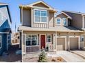 Attractive townhome with a red front door, cozy porch, maintained landscaping, and attached garage for convenient parking at 246 Ash St, Bennett, CO 80102