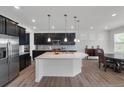 Modern kitchen with an island, stainless steel appliances, dark cabinets, and an adjacent dining area at 5045 Preserve Pl, Firestone, CO 80504