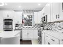Modern kitchen featuring white cabinets, stainless steel appliances, and mosaic backsplash at 21062 E Mansfield Pl, Aurora, CO 80013