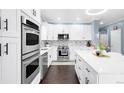 Bright, all-white kitchen with stainless steel appliances and a mosaic tile backsplash at 21062 E Mansfield Pl, Aurora, CO 80013