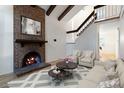 Staged living room with brick fireplace, exposed beams, hardwood floors, and neutral-toned furniture at 4638 S Mobile Way, Aurora, CO 80015