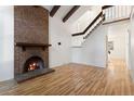 Bright living room boasting a brick fireplace, hardwood floors, vaulted ceilings, and exposed wooden beams at 4638 S Mobile Way, Aurora, CO 80015