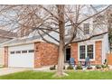 Inviting two-story home featuring a brick facade, attached two-car garage, cozy front porch, and manicured landscaping at 8827 Cactus Flower Way, Highlands Ranch, CO 80126