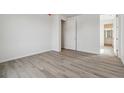 Clean, empty bedroom with modern wood-look flooring, white walls, and an ensuite bathroom at 9062 Telluride Ct, Commerce City, CO 80022