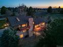 Aerial view of a well-lit home featuring balconies, a stone chimney, and lush surrounding greenery at 9745 Derby Way, Parker, CO 80134