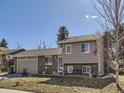 Charming split-level home with a brick and tan exterior, attached two-car garage, basketball hoop and winter foliage at 11002 E Ohio Pl, Aurora, CO 80012