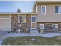 Close up of the front door and address of this split-level home with brick exterior and front yard bench at 11002 E Ohio Pl, Aurora, CO 80012