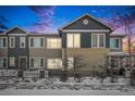 Two-story townhouse exterior with snowy yard and walkway at dusk at 15550 W 64Th Pl # D, Arvada, CO 80007