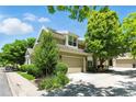 Exterior view of home featuring an attached garage, well-maintained lawn, and mature trees at 4545 S Monaco St # 114, Denver, CO 80237