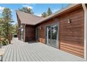 This spacious deck offers sliding glass doors, exterior lighting, and beautiful wood siding at 11760 Baca Rd, Conifer, CO 80433