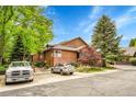 Exterior view of townhouse with wood siding and brick accents, surrounded by lush landscaping and parking at 11820 W 66Th Pl # C, Arvada, CO 80004